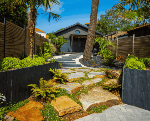 Allée de jardin en diverse matériaux : pierres naturelles, palis d'ardoise, gravillons. Entouré de plantes et d'arbres exotiques. Un jardin de reve crée par au jardin des reves.