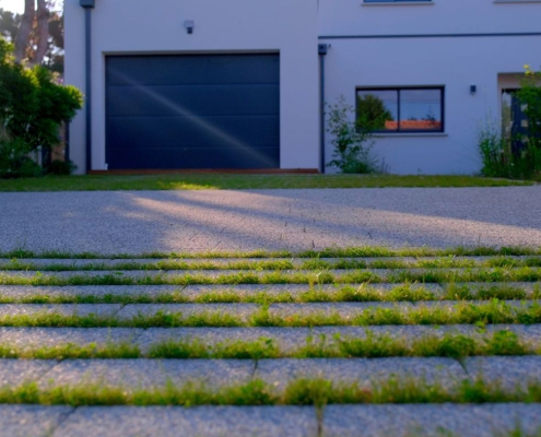 allee-carrossable-paves-engazonnes-entree-maison-au-jardin-des-reves Allée carrossable en pavés engazonnés devant une maison contemporaine, aménagement paysager réalisé par Au Jardin des Rêves.