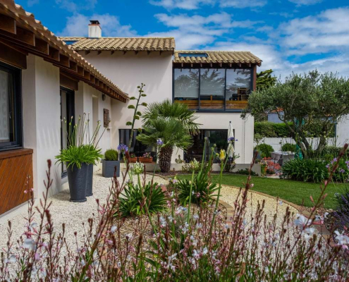 Allée de jardin en gravillons bordée de massifs méditerranéens, avec palmiers, vivaces et arbustes, aménagement paysager à Saint-Viaud réalisé par Au Jardin des Rêves.