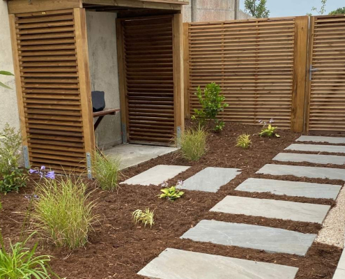 Entrée de jardin paysagée avec pas japonais en dalles, claustras en bois et massifs végétalisés à Frossay.