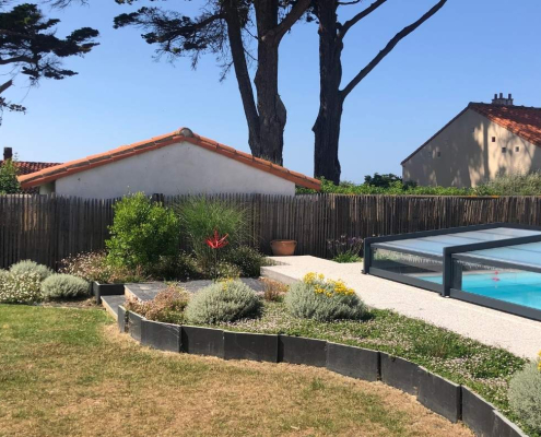 amenagement-jardin-piscine-massifs-au-jardin-des-reves Jardin aménagé avec piscine couverte, massifs paysagers et bordures courbes, réalisation par Au Jardin des Rêves à Saint-Brévin-les-Pins.