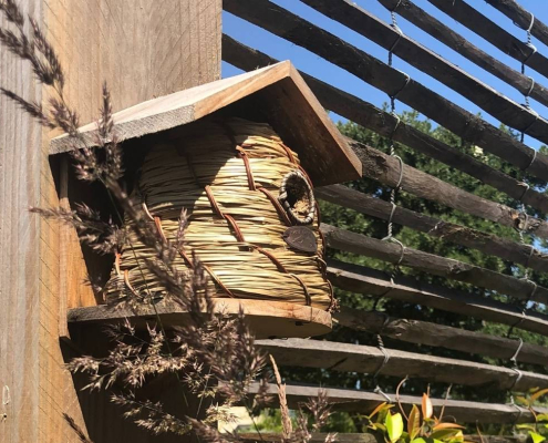 Nichoir pour oiseaux fixé sur une structure en bois dans un jardin.