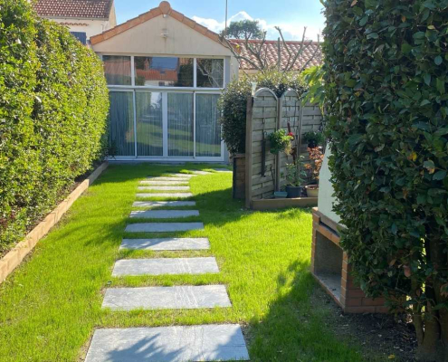 Allée de jardin en pas japonais posés dans le gazon, bordée de haies taillées, aménagement paysager réalisé par Au Jardin des Rêves à Frossay.