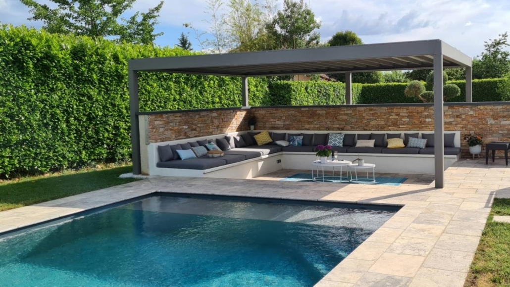 amenagement-piscine-pergola-jardin-exterieur Piscine moderne avec terrasse en pierre, pergola bioclimatique et salon extérieur dans un jardin paysager
